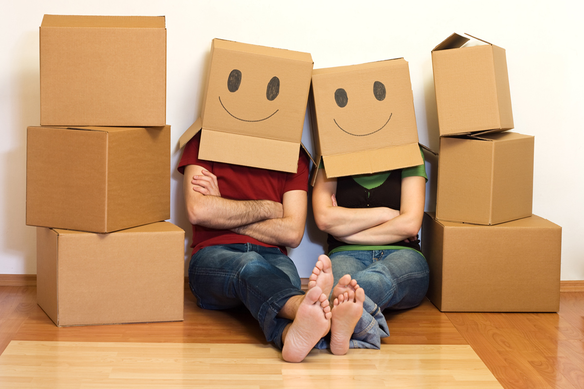 Couple sitting with moving boxes on their heads